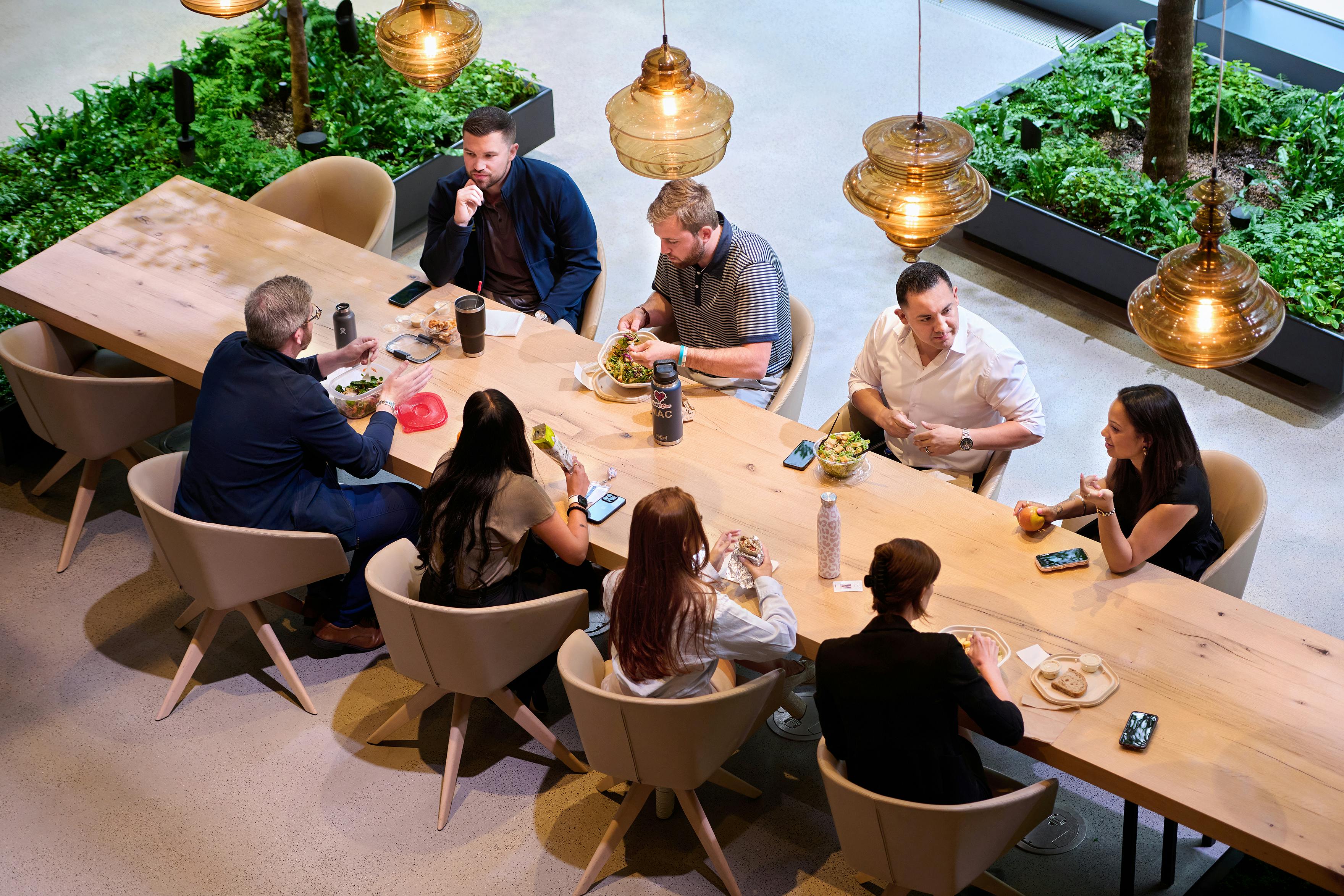 A group of employees gathers around a table in the office lobby for lunch