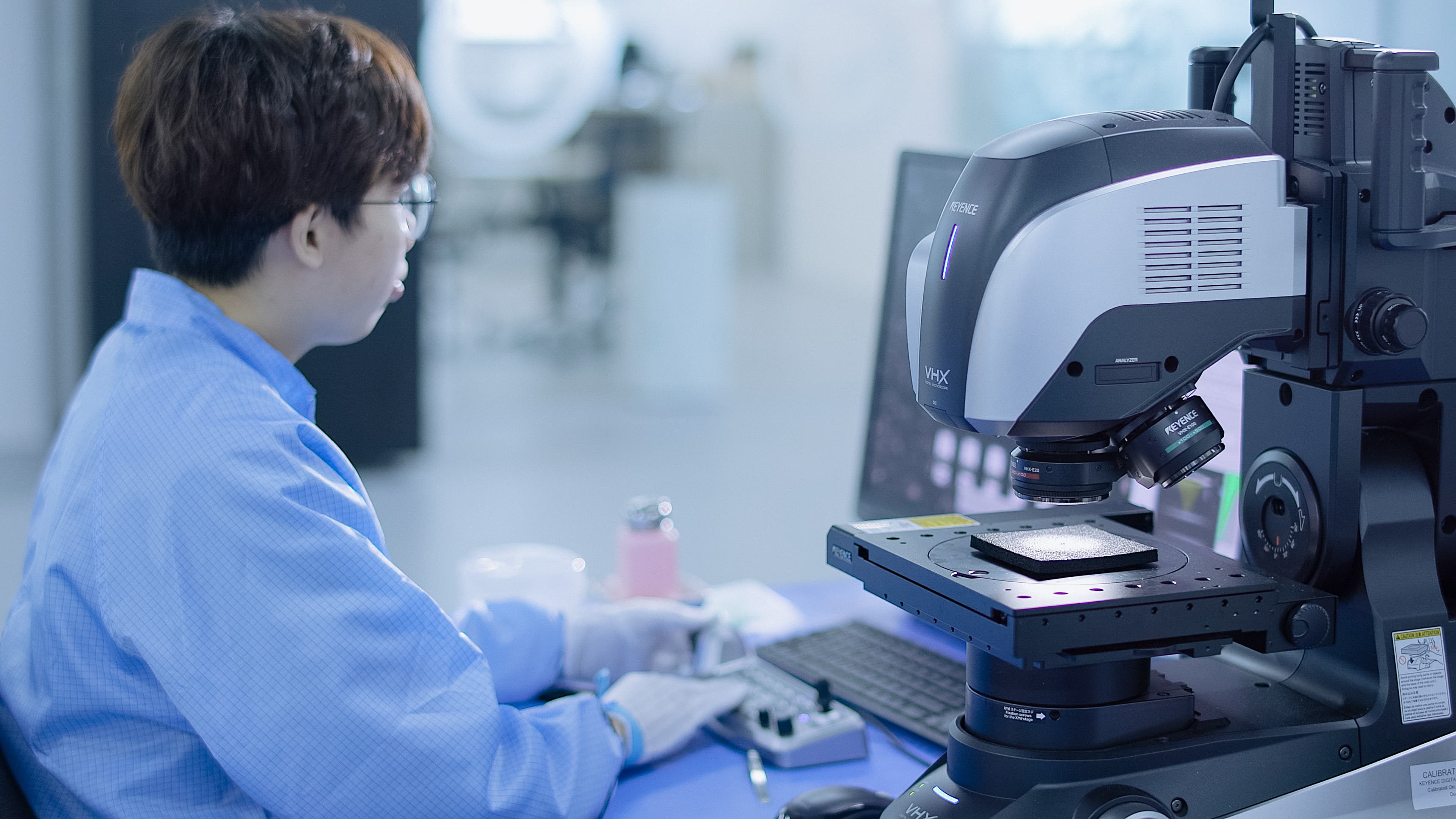 Fusion Worldwide quality control inspector examining parts on a computer and microscope