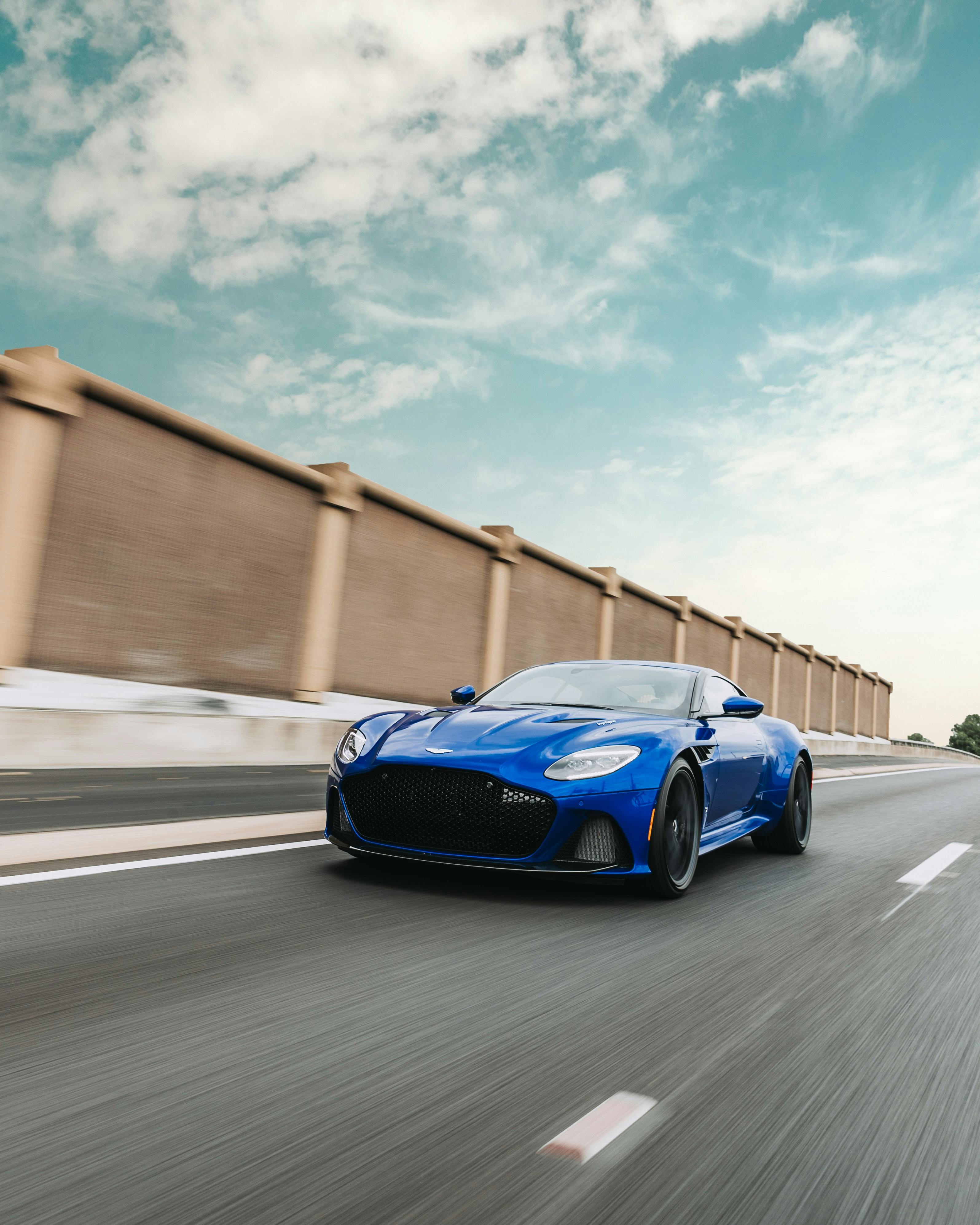 Blue sports car driving quickly on two-lane road