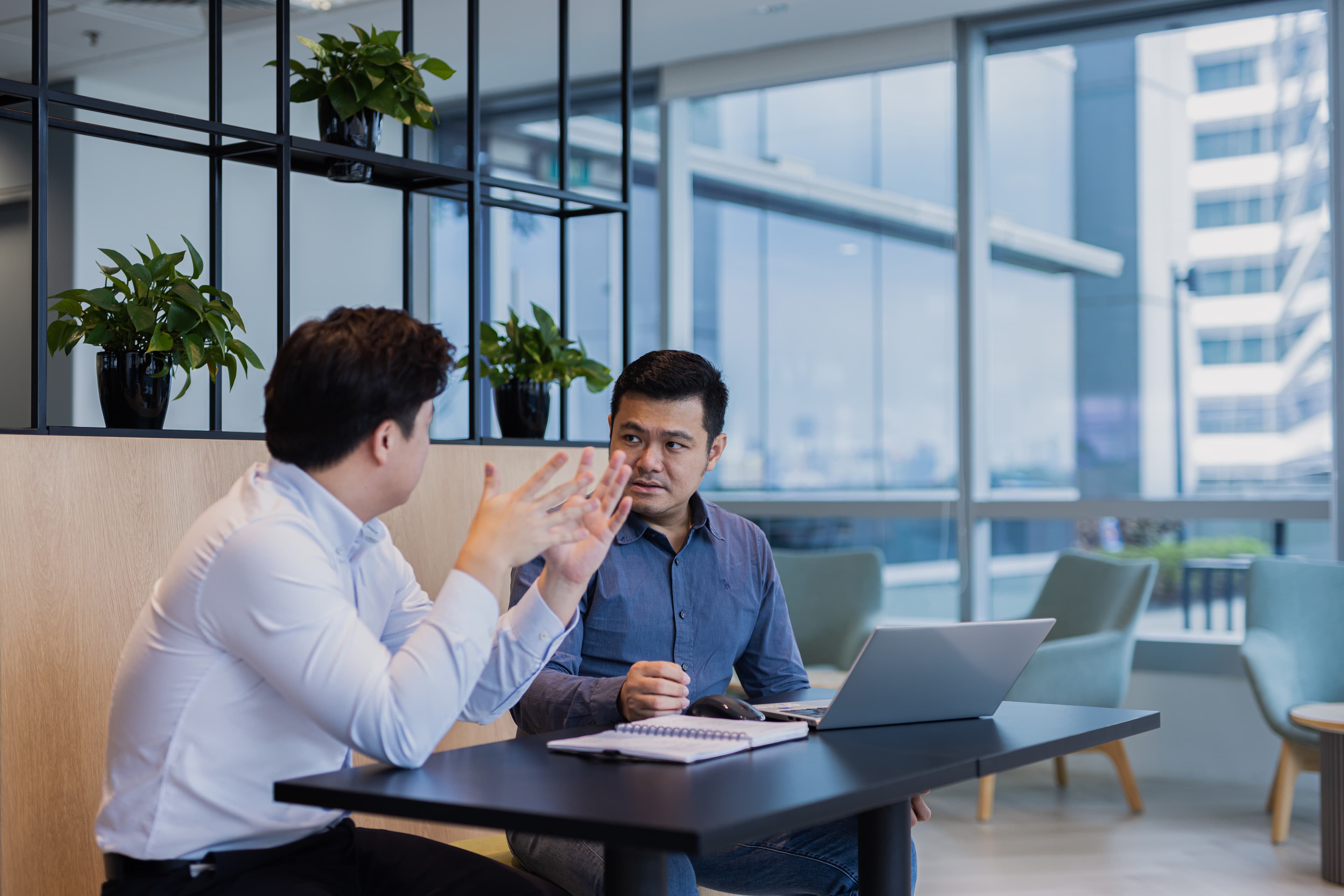 Two Fusion Worldwide APAC employees sitting at a table with notebooks and a laptop