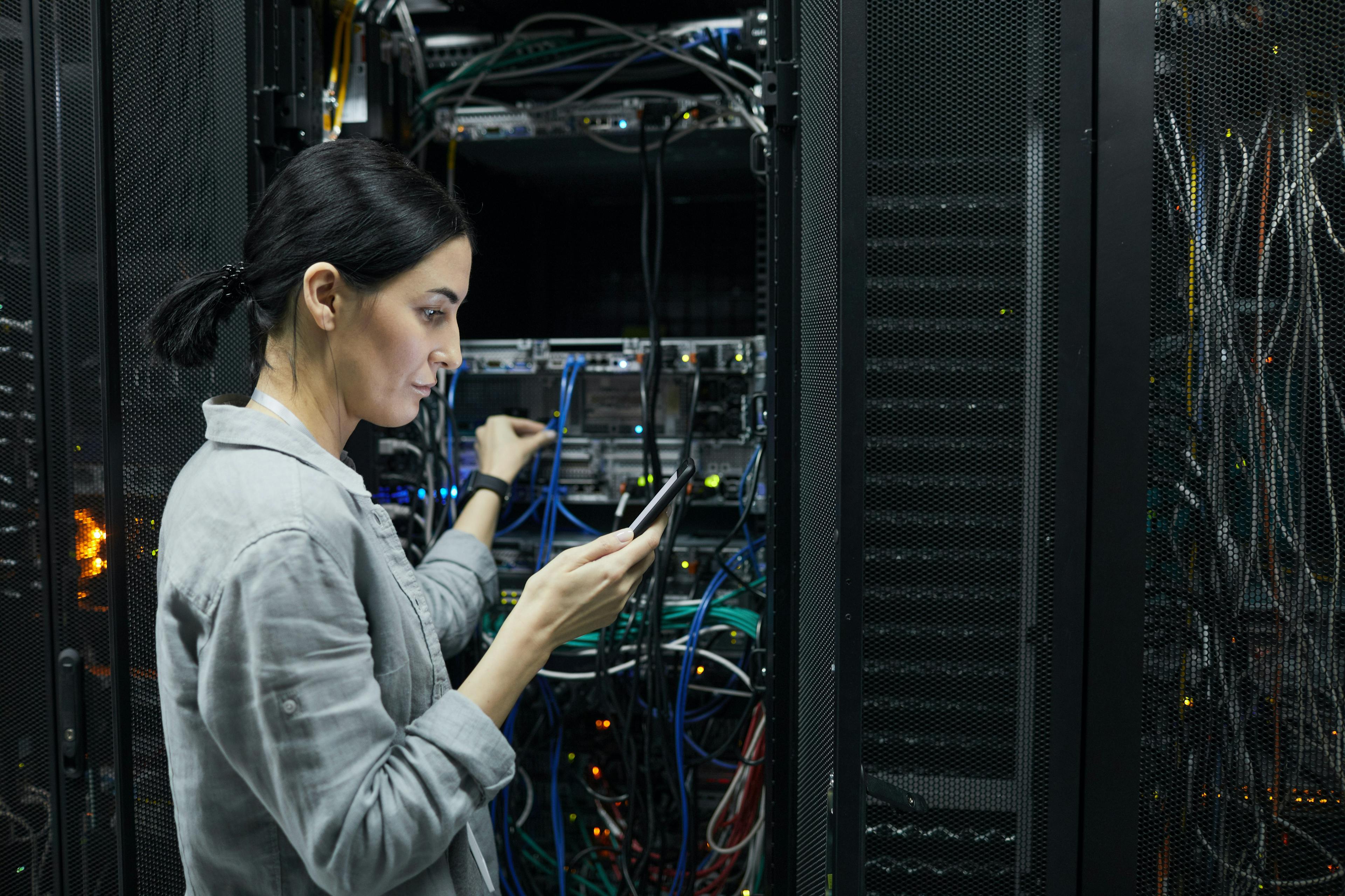 Worker standing in front of a rack of servers to test a connection