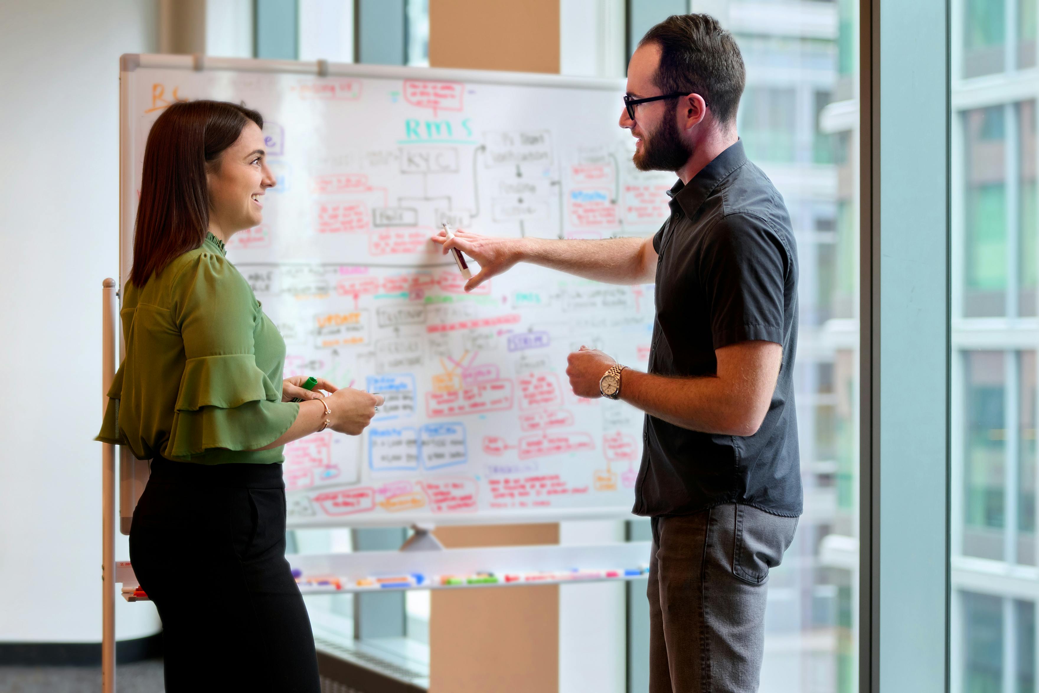 Two employees standing at a whiteboard in a conference room