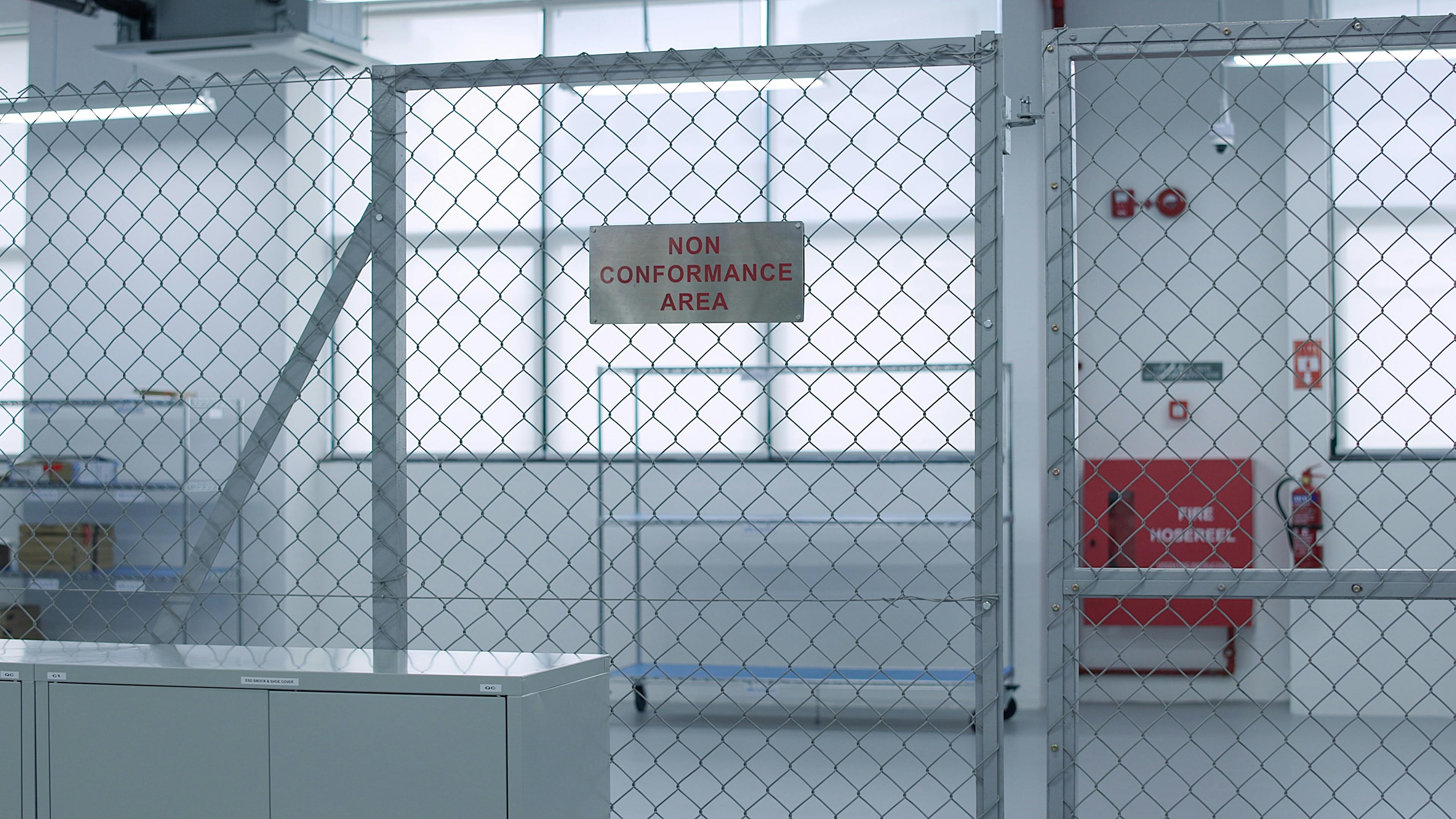 A mental fence in a Fusion Worldwide warehouse with a sign that reads "Non Conformance Area"